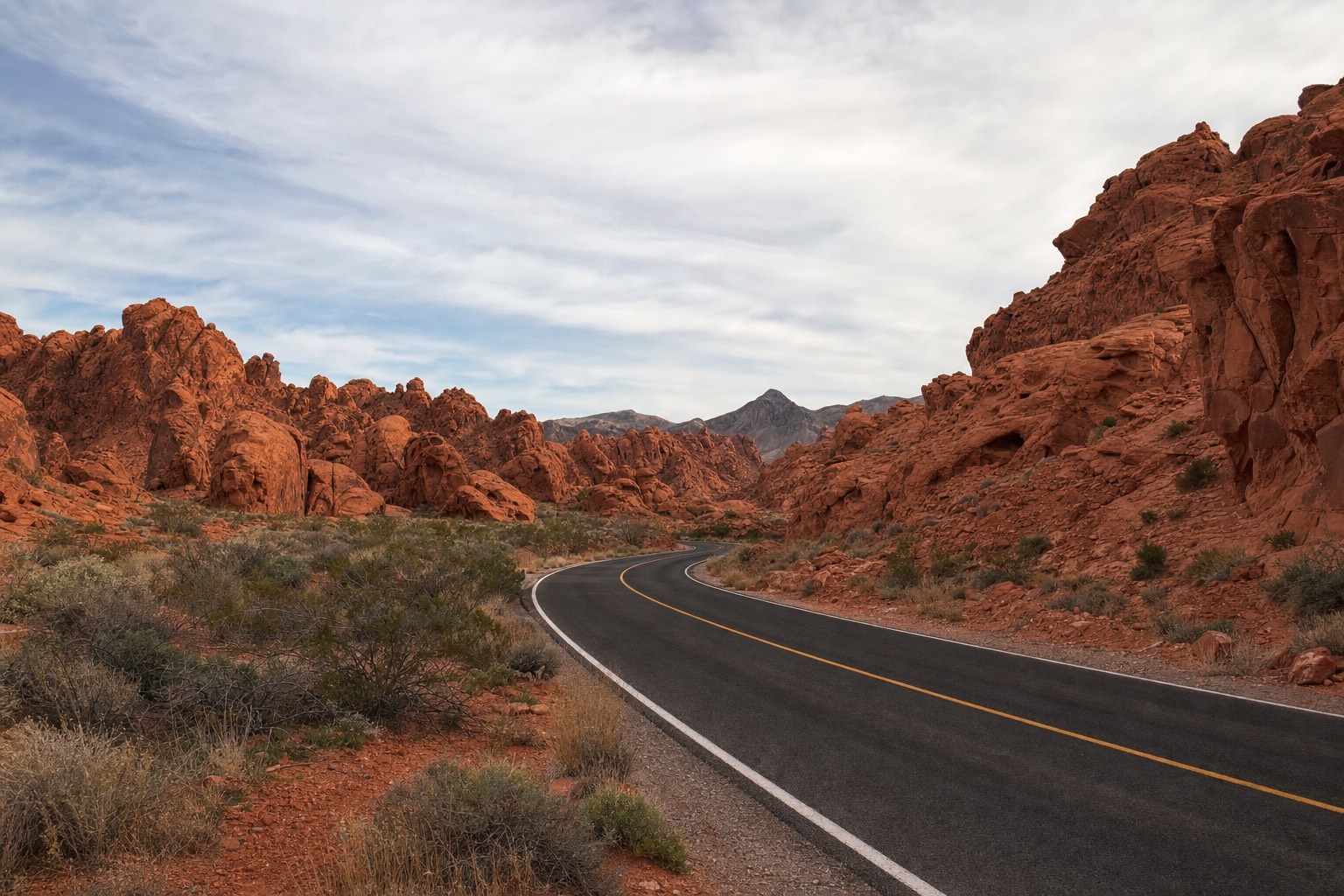A paved scenic desert road curving through red sandstone formations